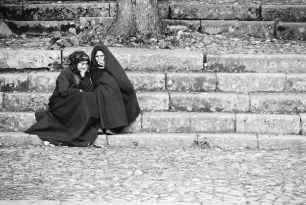 This is one of my favourite photographs. Titled “O Cochicho” (“The Whisper”), it shows two elderly women sitting on the church steps, dressed in traditional burel capes. Typical village devotees, they quietly share the latest gossip of the village.